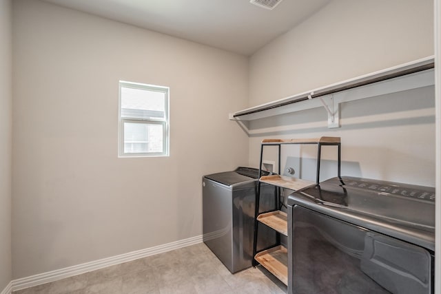 clothes washing area with light tile patterned flooring, laundry area, washer and dryer, and baseboards