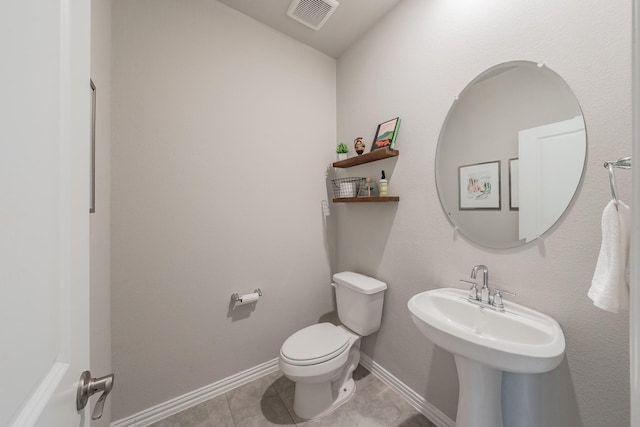 half bath featuring baseboards, visible vents, a sink, tile patterned flooring, and toilet