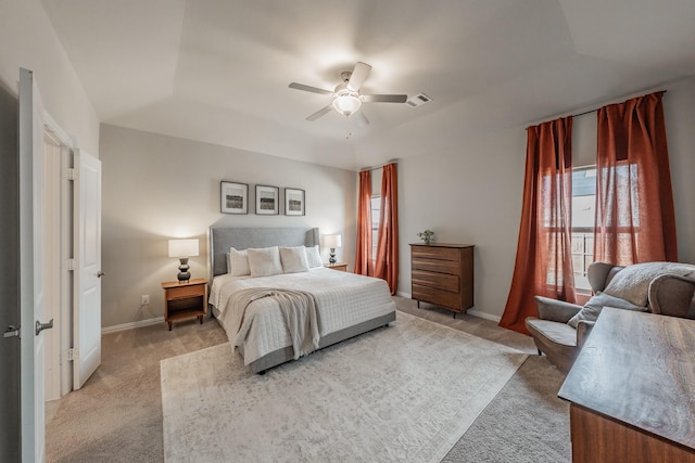 carpeted bedroom featuring a tray ceiling, baseboards, visible vents, and a ceiling fan