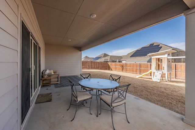 view of patio featuring a playground, outdoor dining area, and a fenced backyard