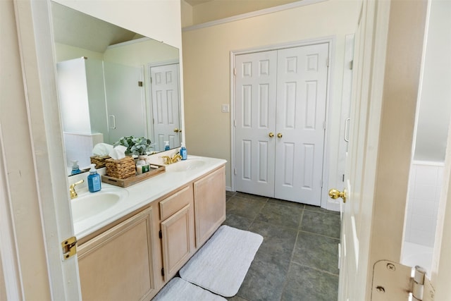 bathroom featuring double vanity, a shower, and a sink