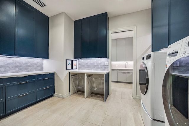 washroom featuring visible vents, a sink, cabinet space, and washer / clothes dryer
