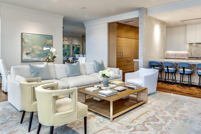 living area with crown molding, light wood finished floors, and a chandelier