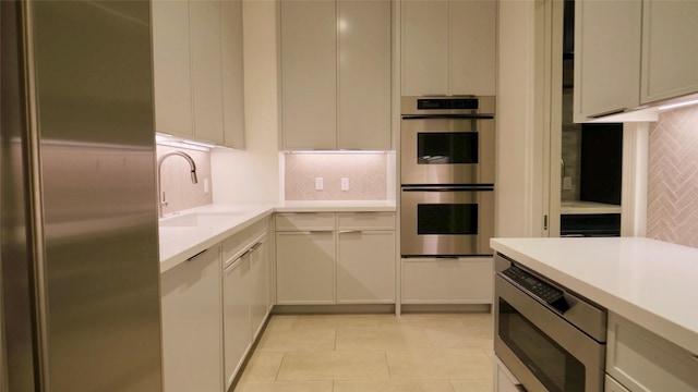 kitchen with a sink, stainless steel appliances, tasteful backsplash, and light countertops