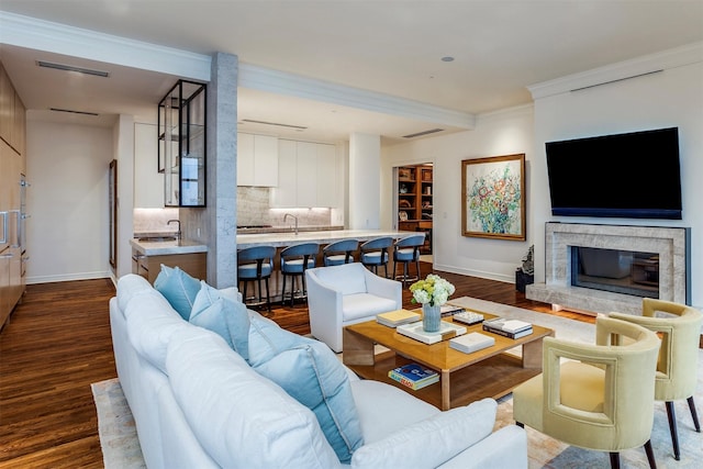 living room with visible vents, ornamental molding, baseboards, a stone fireplace, and dark wood-type flooring