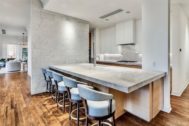 kitchen featuring a breakfast bar area, visible vents, a sink, and gas stovetop