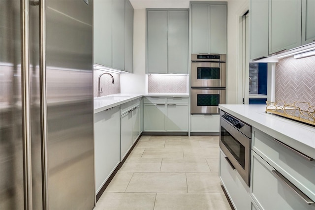 kitchen featuring a sink, appliances with stainless steel finishes, decorative backsplash, and light countertops