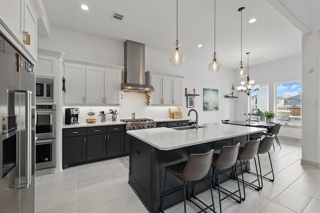 kitchen featuring a sink, tasteful backsplash, appliances with stainless steel finishes, wall chimney exhaust hood, and light countertops