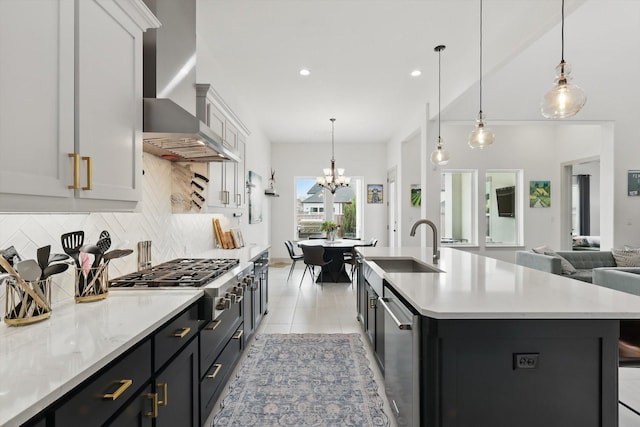 kitchen with open floor plan, stainless steel appliances, wall chimney exhaust hood, light countertops, and decorative backsplash