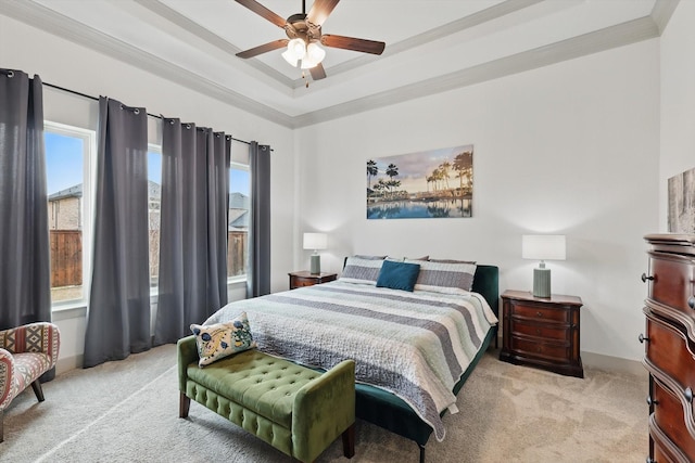 carpeted bedroom featuring a tray ceiling, ornamental molding, and a ceiling fan