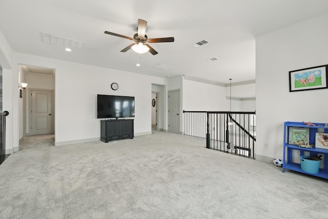 unfurnished living room with visible vents, carpet flooring, attic access, and ceiling fan