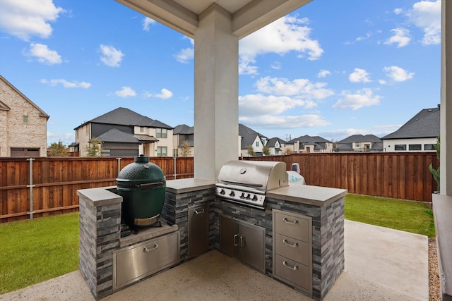 view of patio / terrace featuring a fenced backyard, a residential view, area for grilling, and an outdoor kitchen