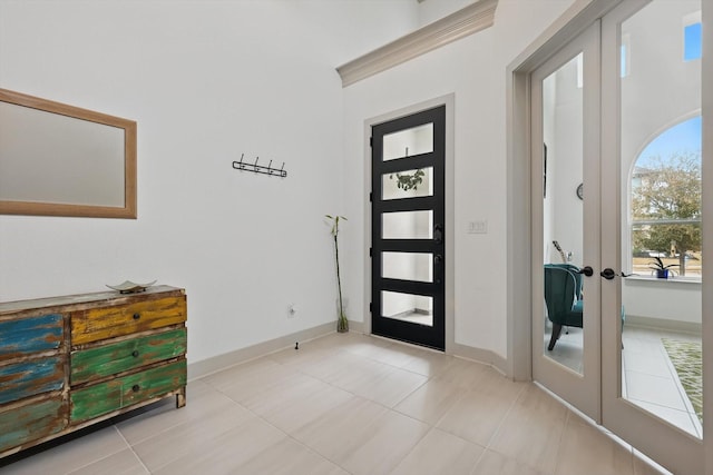 entryway with crown molding, light tile patterned floors, french doors, and baseboards