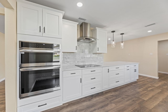 kitchen featuring visible vents, wall chimney range hood, decorative backsplash, stainless steel double oven, and dark wood-style flooring