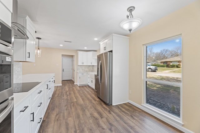 kitchen featuring backsplash, dark wood-type flooring, pendant lighting, appliances with stainless steel finishes, and white cabinets