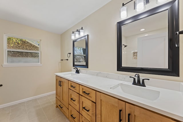 bathroom featuring tile patterned flooring, double vanity, baseboards, and a sink