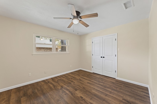 unfurnished bedroom featuring a ceiling fan, baseboards, visible vents, dark wood-type flooring, and a closet