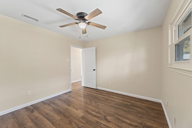 spare room with a ceiling fan, dark wood-style floors, visible vents, and baseboards