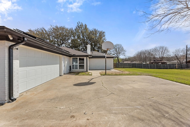 exterior space with driveway, fence, a yard, an attached garage, and a chimney