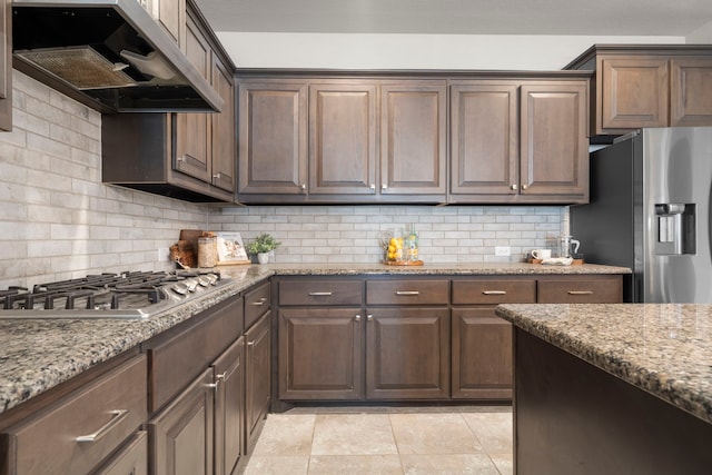 kitchen with ventilation hood, stainless steel appliances, light stone counters, and backsplash