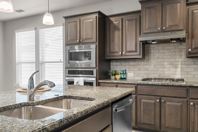 kitchen featuring under cabinet range hood, tasteful backsplash, appliances with stainless steel finishes, and a sink