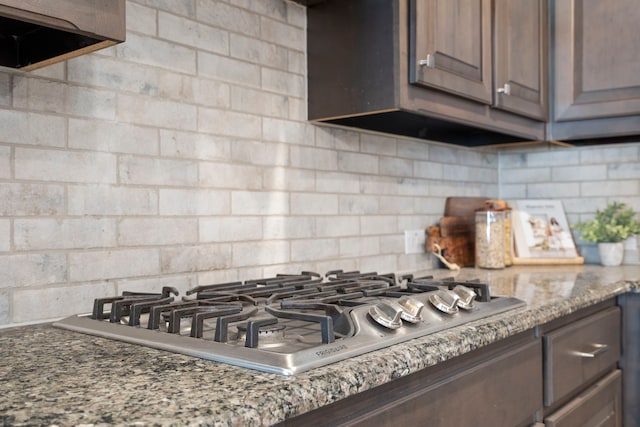 interior details with stainless steel gas cooktop, decorative backsplash, and light stone counters