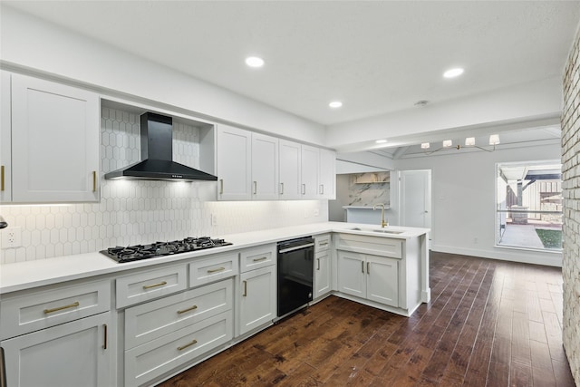 kitchen with black appliances, a sink, backsplash, a peninsula, and wall chimney range hood