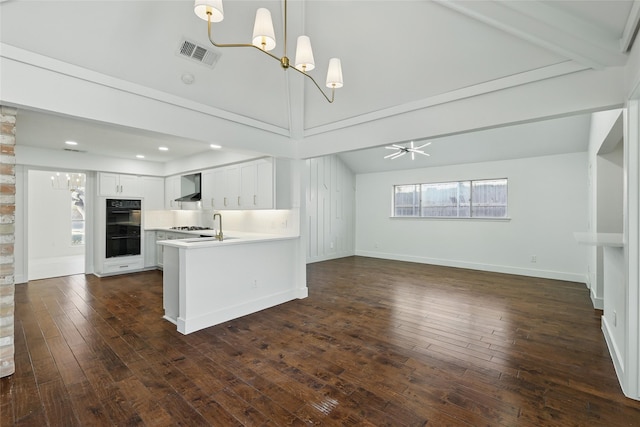 kitchen featuring visible vents, dobule oven black, open floor plan, wall chimney exhaust hood, and a chandelier