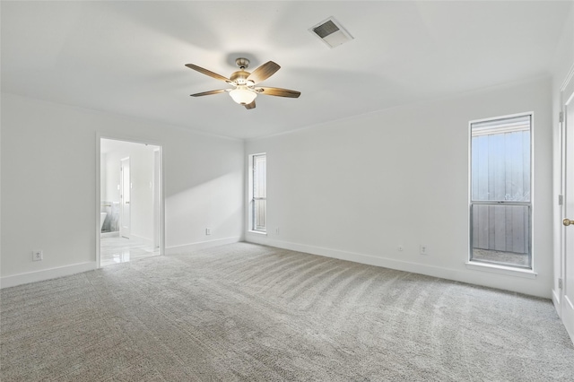 carpeted spare room featuring visible vents, baseboards, and ceiling fan