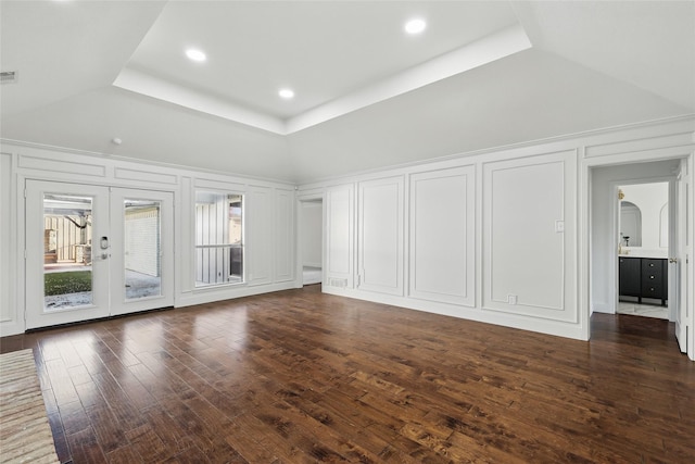 unfurnished living room featuring visible vents, recessed lighting, a decorative wall, a raised ceiling, and dark wood-style flooring