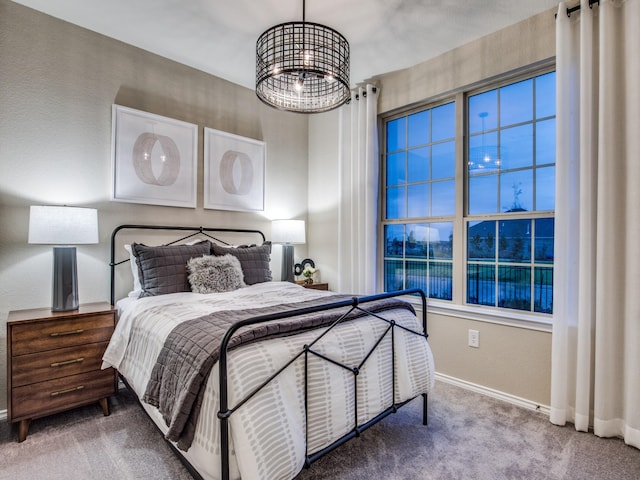 carpeted bedroom featuring an inviting chandelier and baseboards