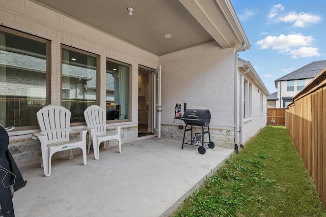 view of patio with fence and a grill