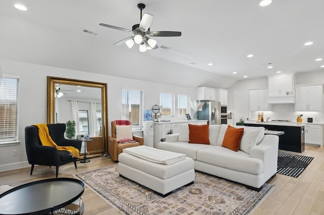 living room with a wealth of natural light, visible vents, and ceiling fan