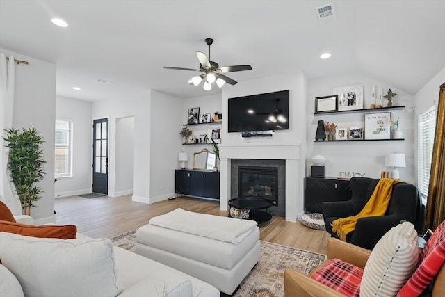 living room featuring visible vents, ceiling fan, a glass covered fireplace, and wood finished floors