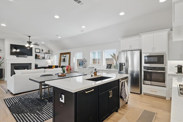 kitchen with light countertops, dark cabinetry, stainless steel appliances, a ceiling fan, and a sink