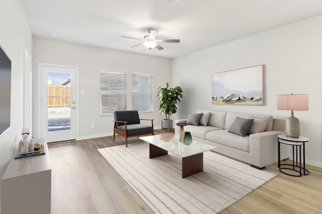 living room featuring a ceiling fan, light wood-style floors, and baseboards