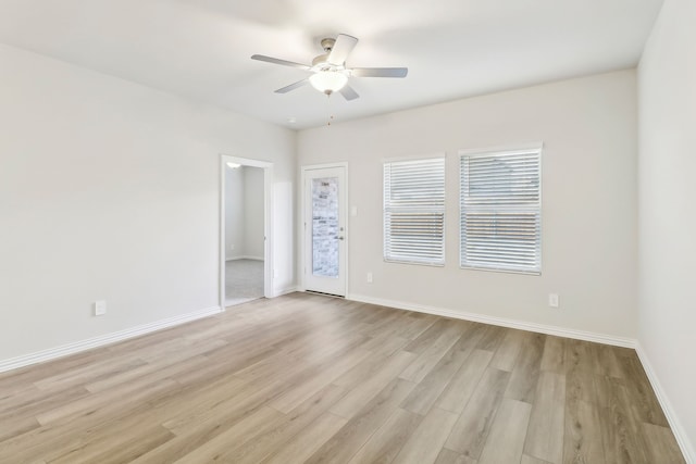 spare room with baseboards, light wood-style flooring, and a ceiling fan