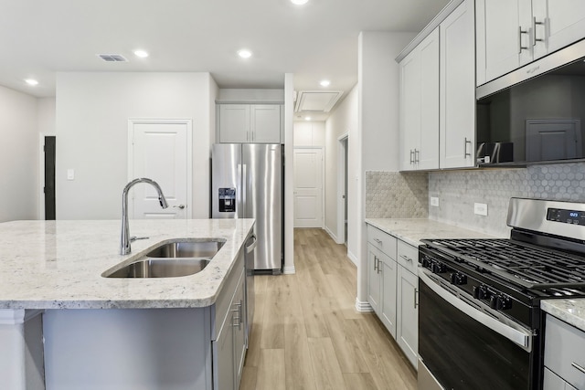 kitchen with tasteful backsplash, visible vents, gray cabinetry, stainless steel appliances, and a sink