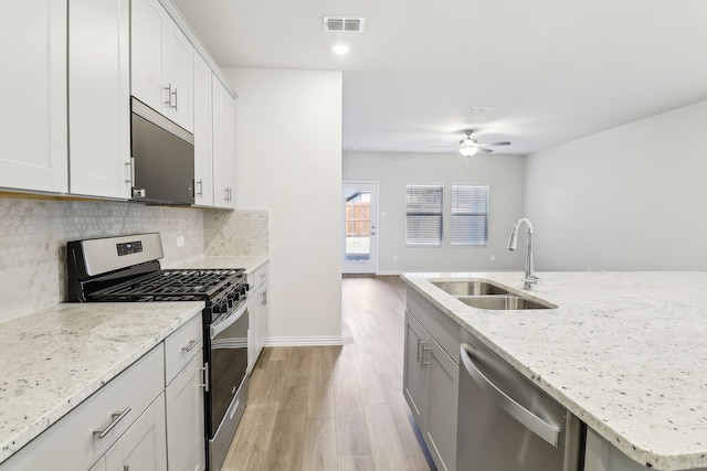 kitchen featuring visible vents, backsplash, ceiling fan, appliances with stainless steel finishes, and a sink