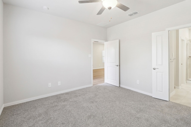 unfurnished bedroom featuring visible vents, connected bathroom, baseboards, light colored carpet, and a ceiling fan