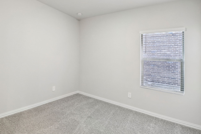 carpeted empty room featuring baseboards