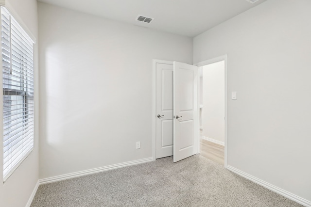 carpeted spare room with baseboards and visible vents