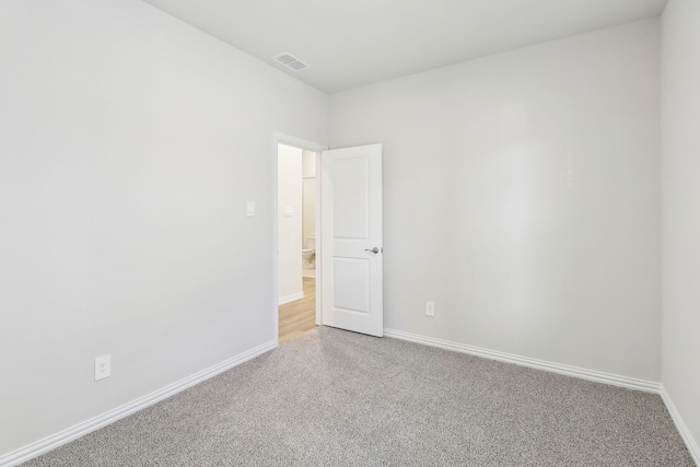 empty room with visible vents, baseboards, and light colored carpet