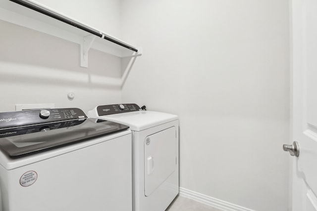 washroom with baseboards, laundry area, and washer and clothes dryer