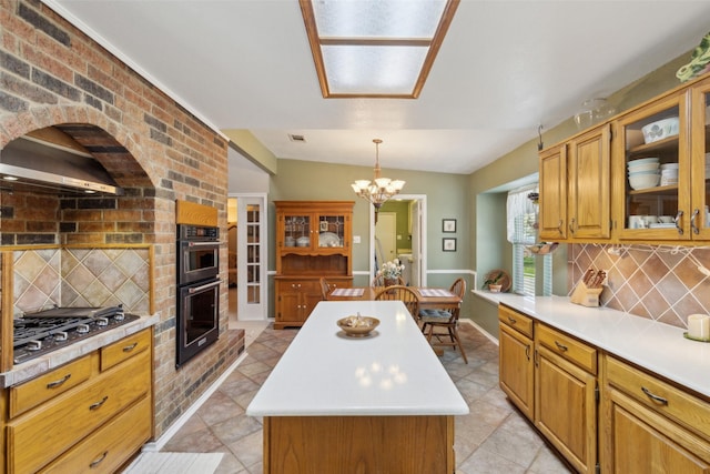 kitchen with a center island, light countertops, a notable chandelier, gas cooktop, and dobule oven black