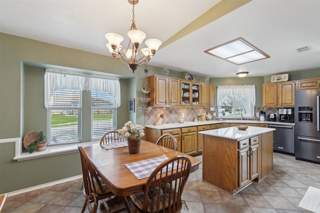 kitchen featuring fridge with ice dispenser, a sink, a kitchen island, light countertops, and dishwasher