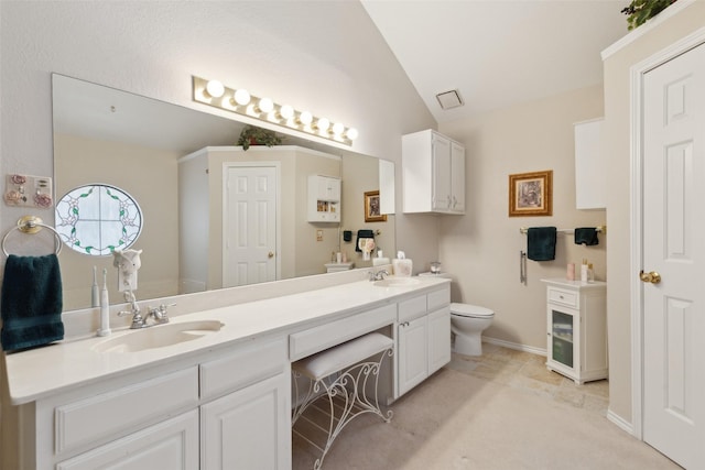 bathroom featuring vaulted ceiling, toilet, double vanity, and a sink