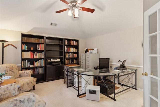 home office featuring a ceiling fan, vaulted ceiling, light colored carpet, and visible vents