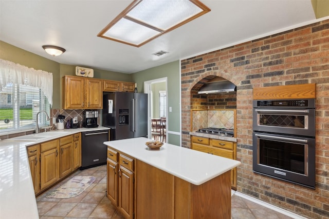 kitchen featuring visible vents, a sink, appliances with stainless steel finishes, wall chimney range hood, and tasteful backsplash