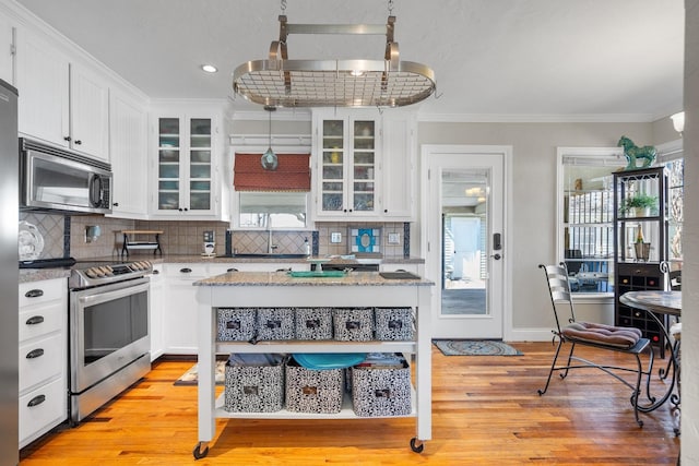 kitchen with white cabinetry, stainless steel appliances, and ornamental molding